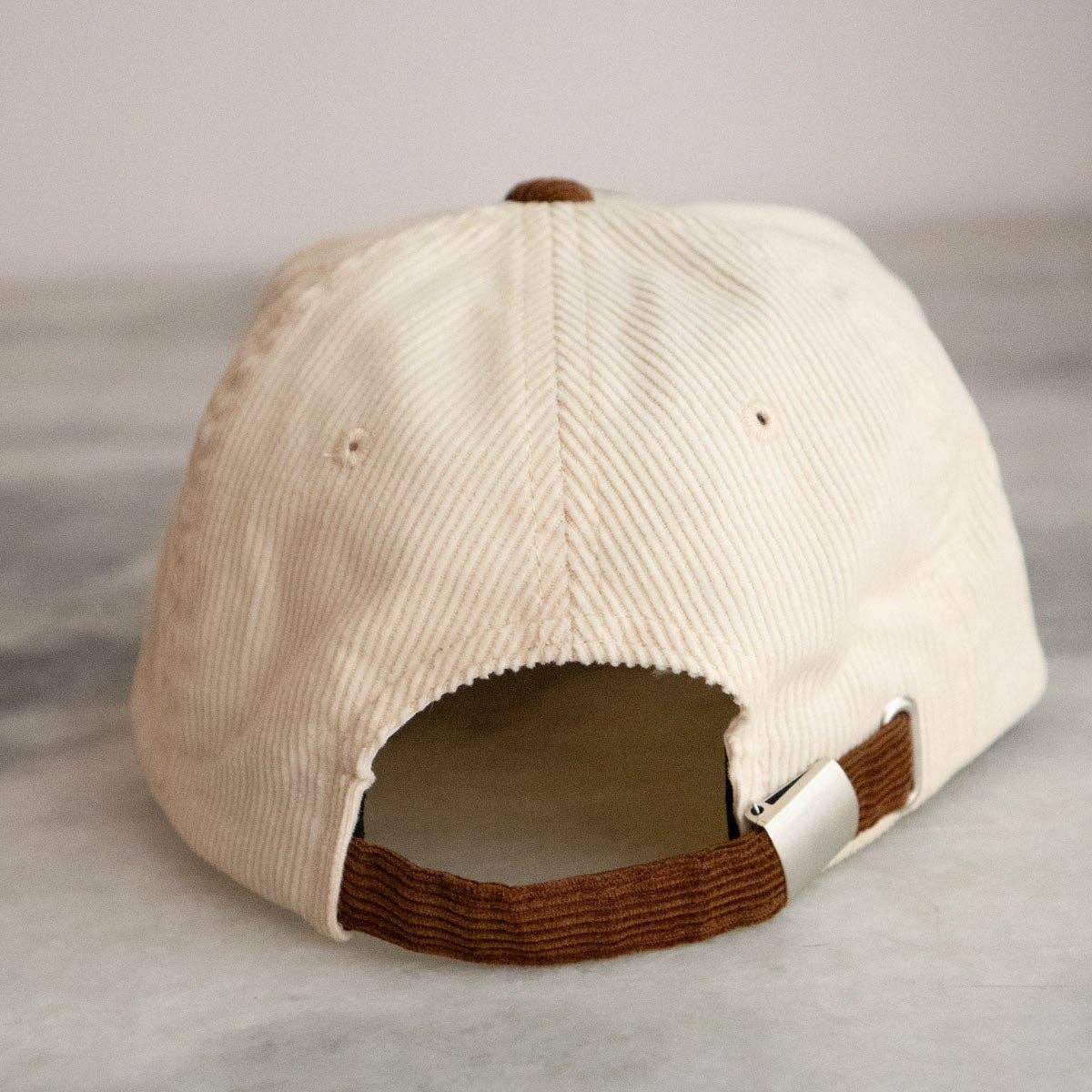 Beige cap with brown brim on a light gray background