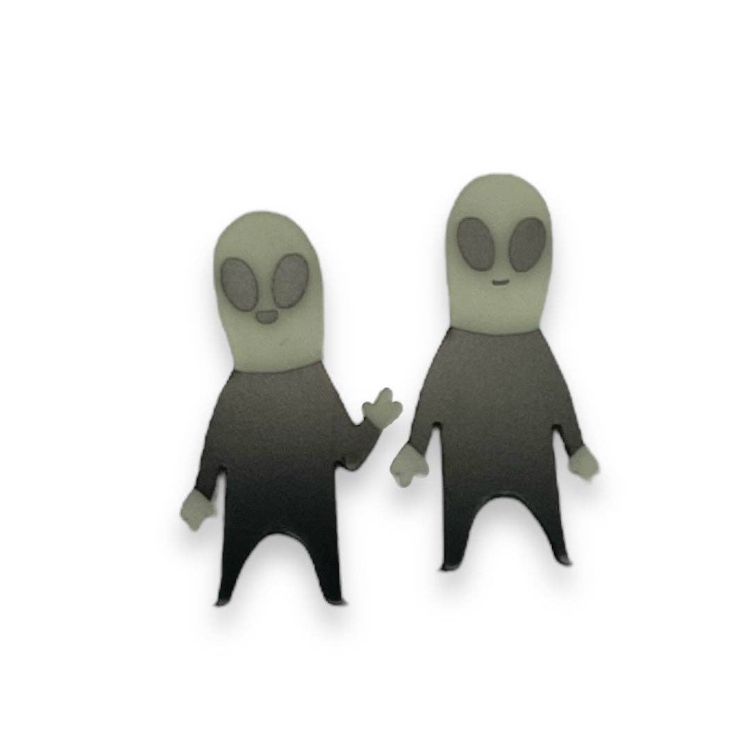 Two alien-shaped earrings on a white background