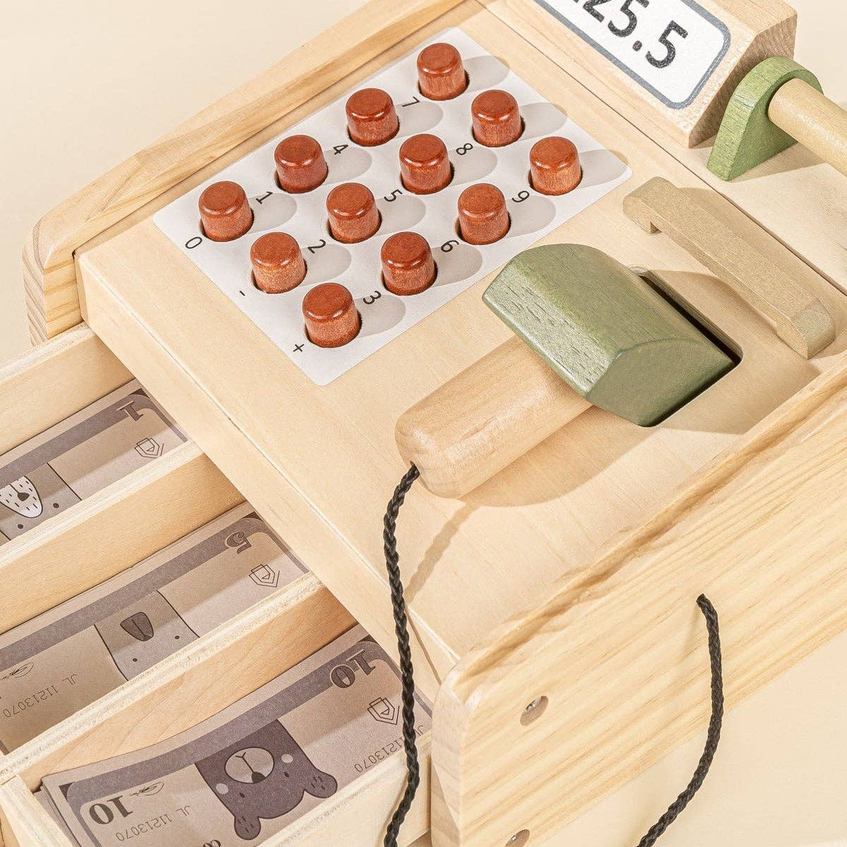 Wooden toy cash register with buttons and a display on a beige background