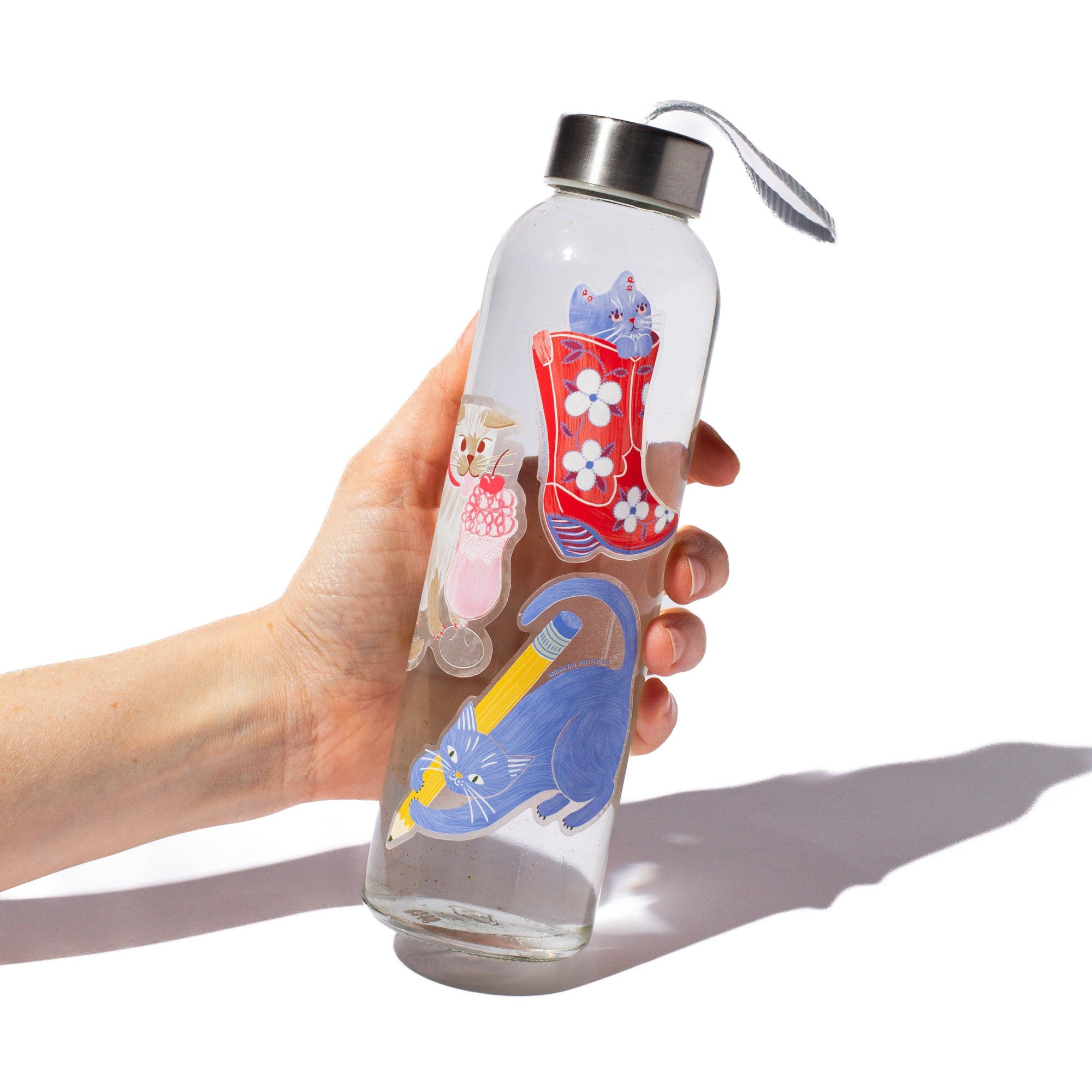 Clear water bottle with colorful designs held by a hand on a white background