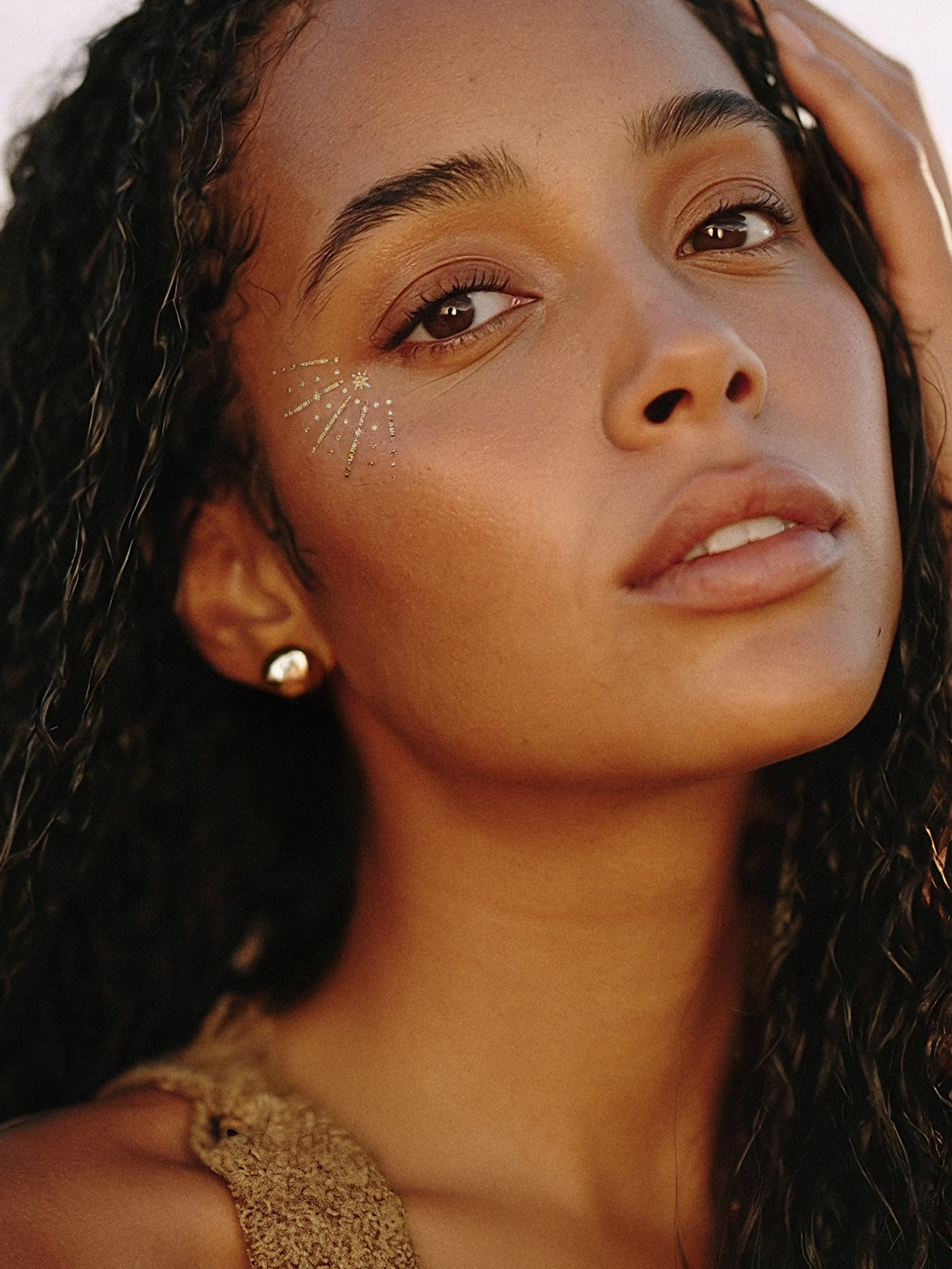 Close-up of a woman with decorative face paint and a gold earring.