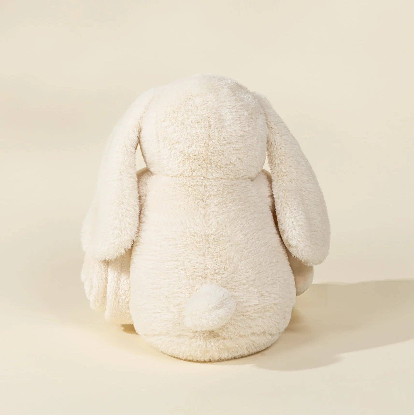White plush bunny toy on a beige background
