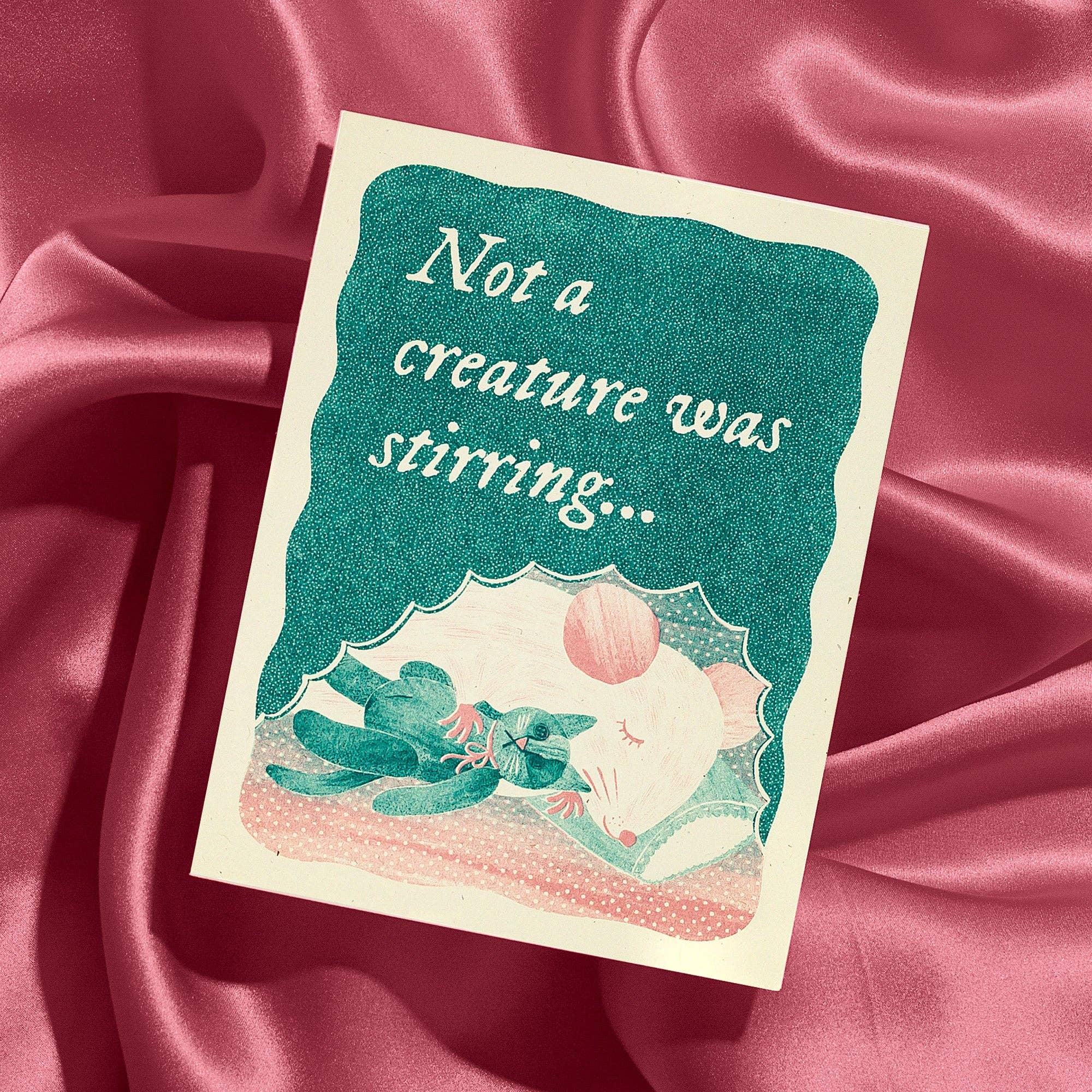 Card with illustration of a mouse and frog under an umbrella, text 'Not a creature was stirring', on a pink satin background.