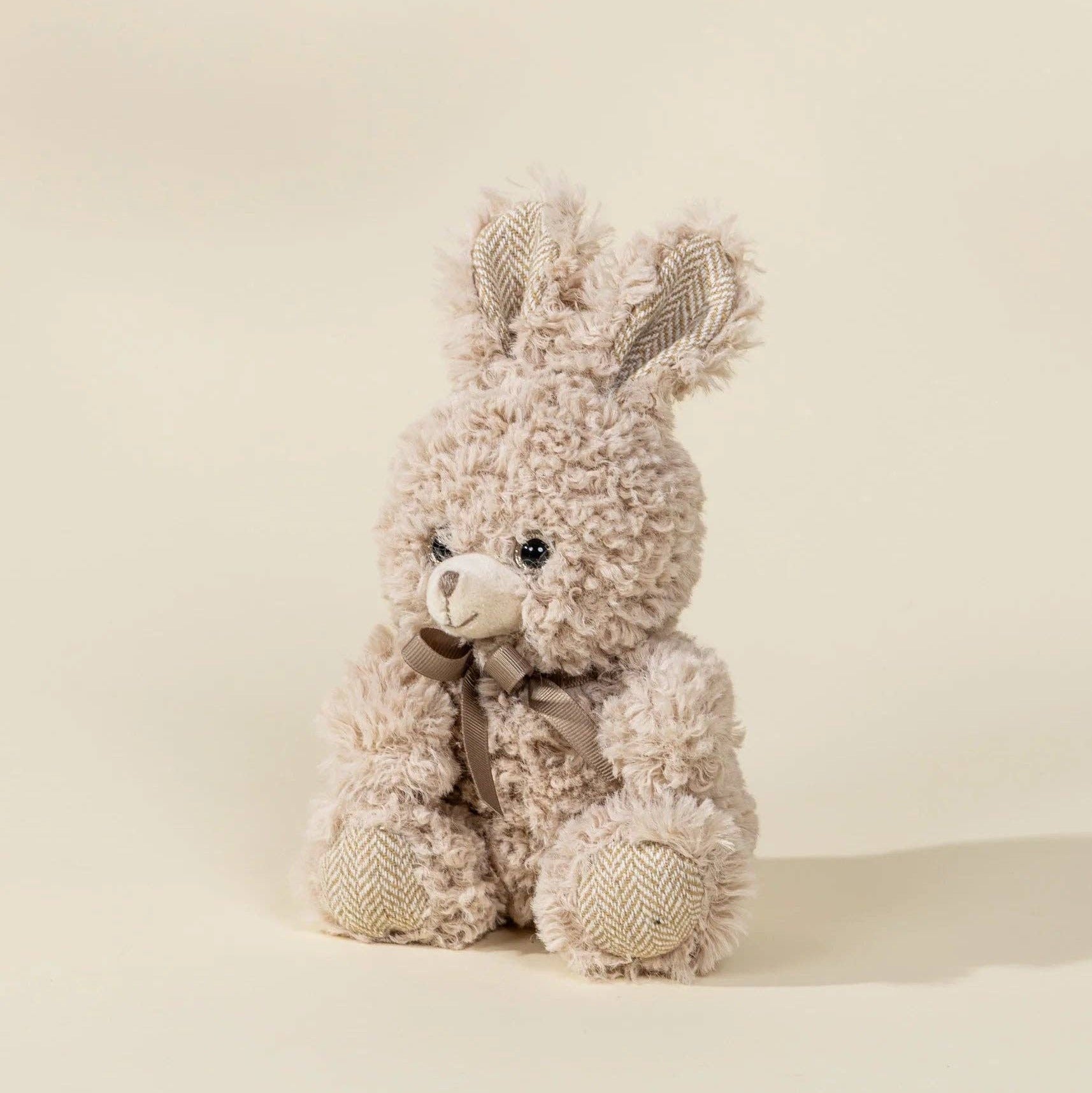 Plush bunny toy with textured fur on a beige background