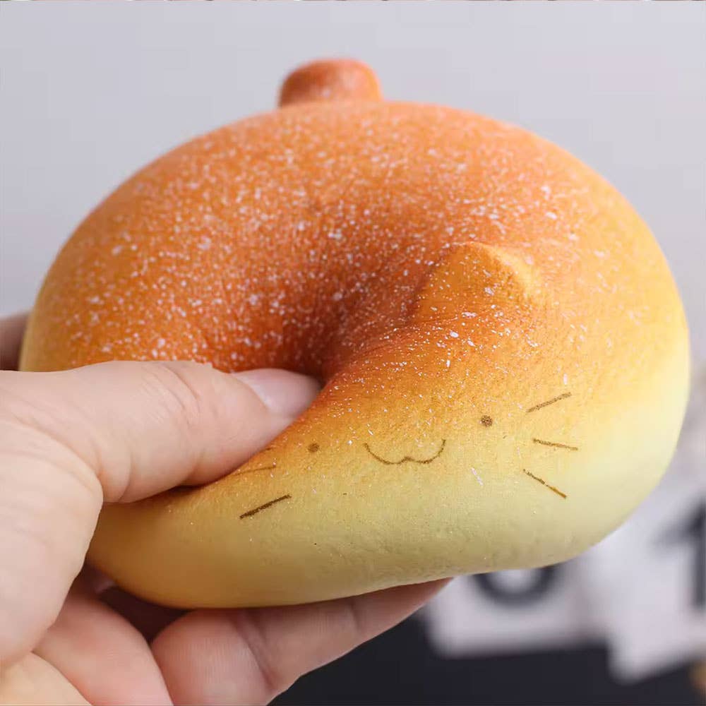 Hand holding a round, brown bread roll with a smiley face on a blurred background