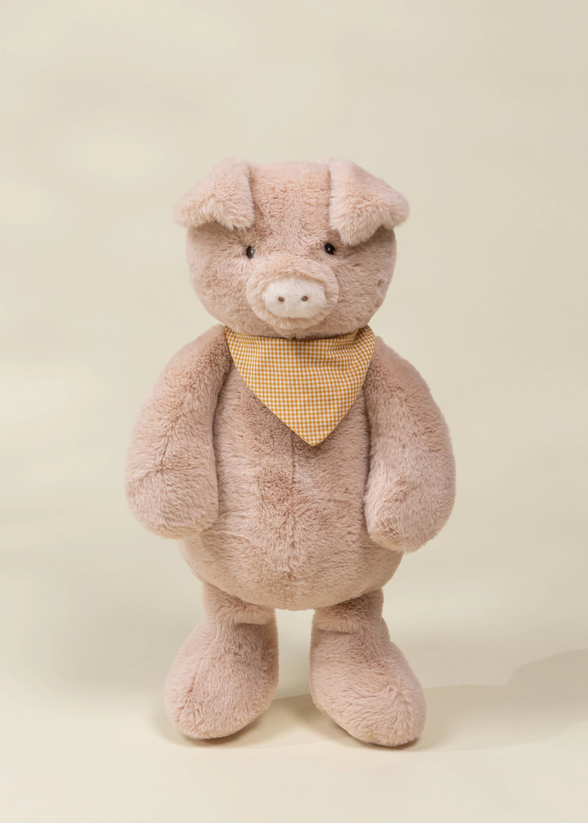 Plush toy pig with a yellow bandana on a beige background