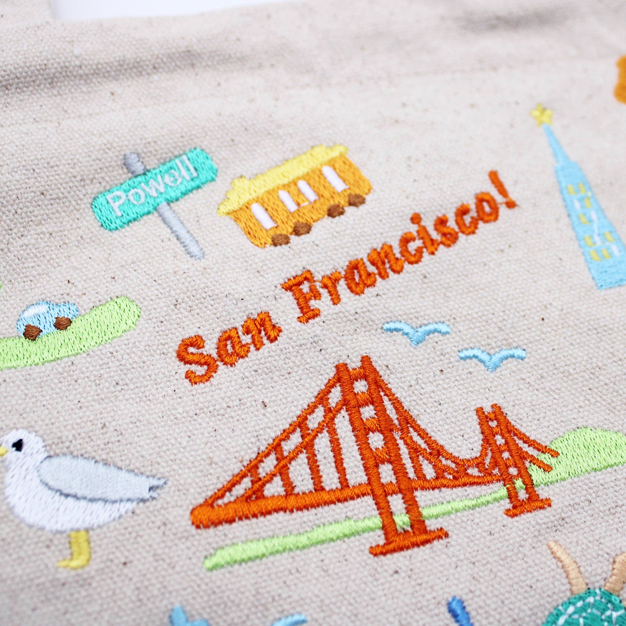 Embroidered design of San Francisco with Golden Gate Bridge, seagull, and other elements on fabric.