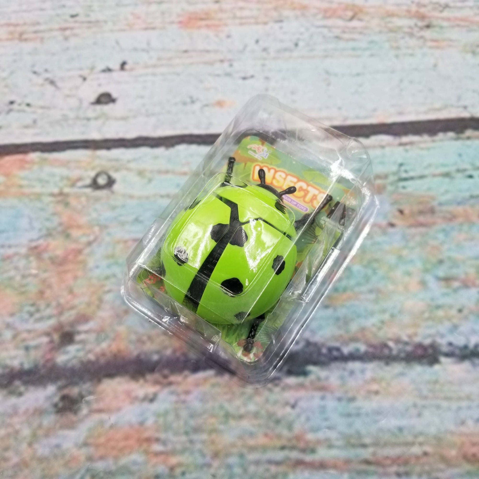 Green toy car in clear packaging on a textured surface