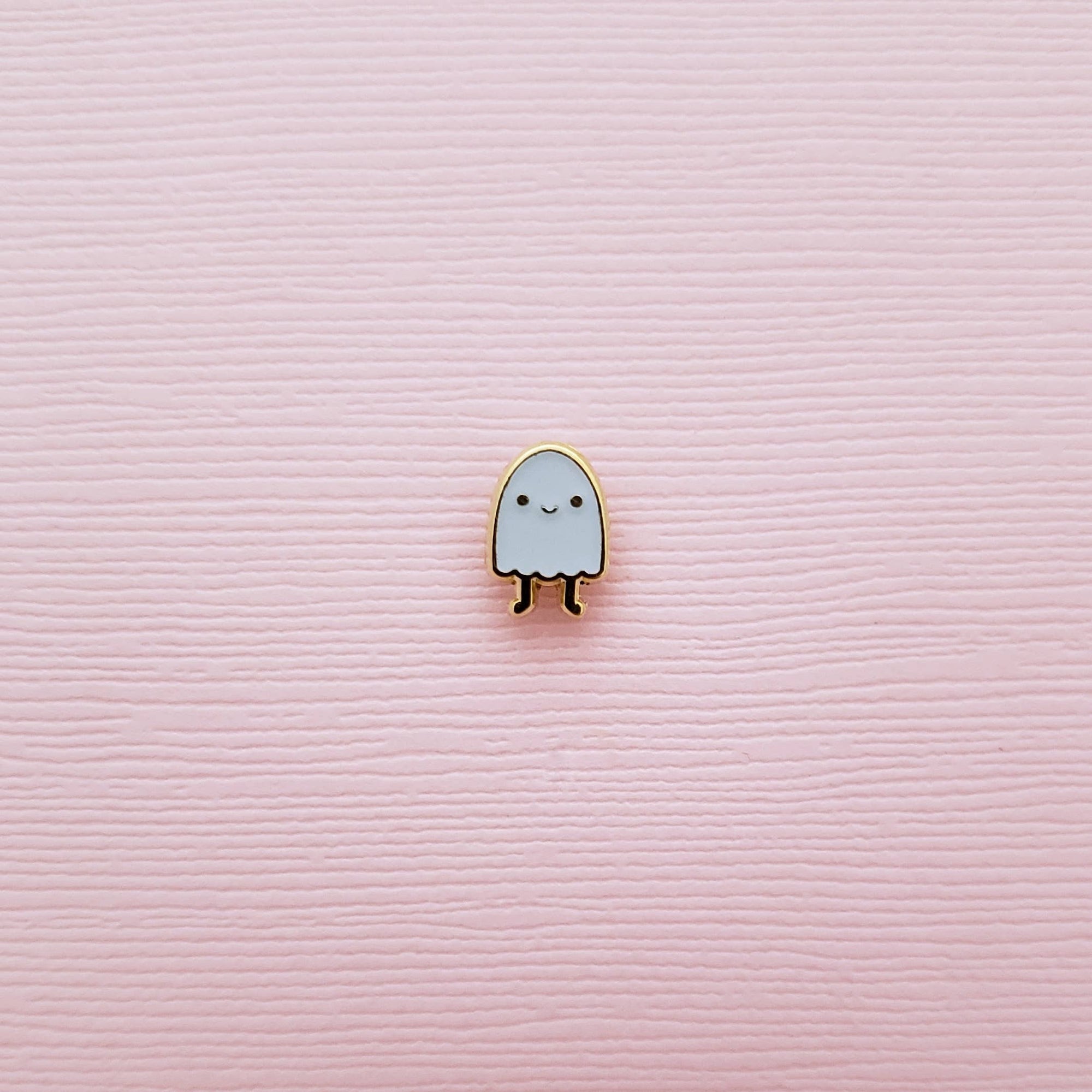 Ghost-shaped pin on a pink textured background