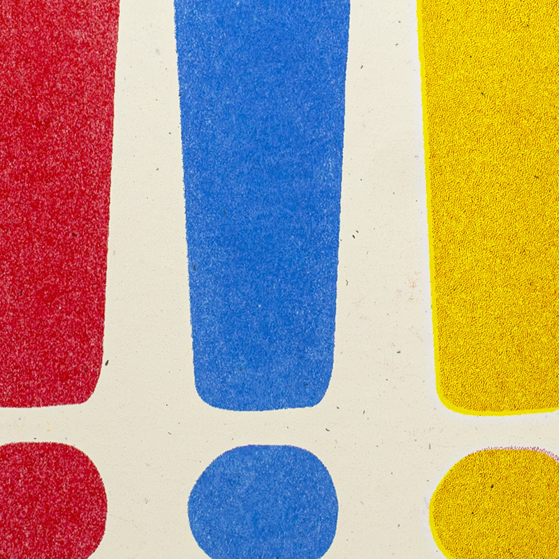 A close-up of a colorful abstract pattern with large textured red, blue, and yellow shapes on an off-white background.