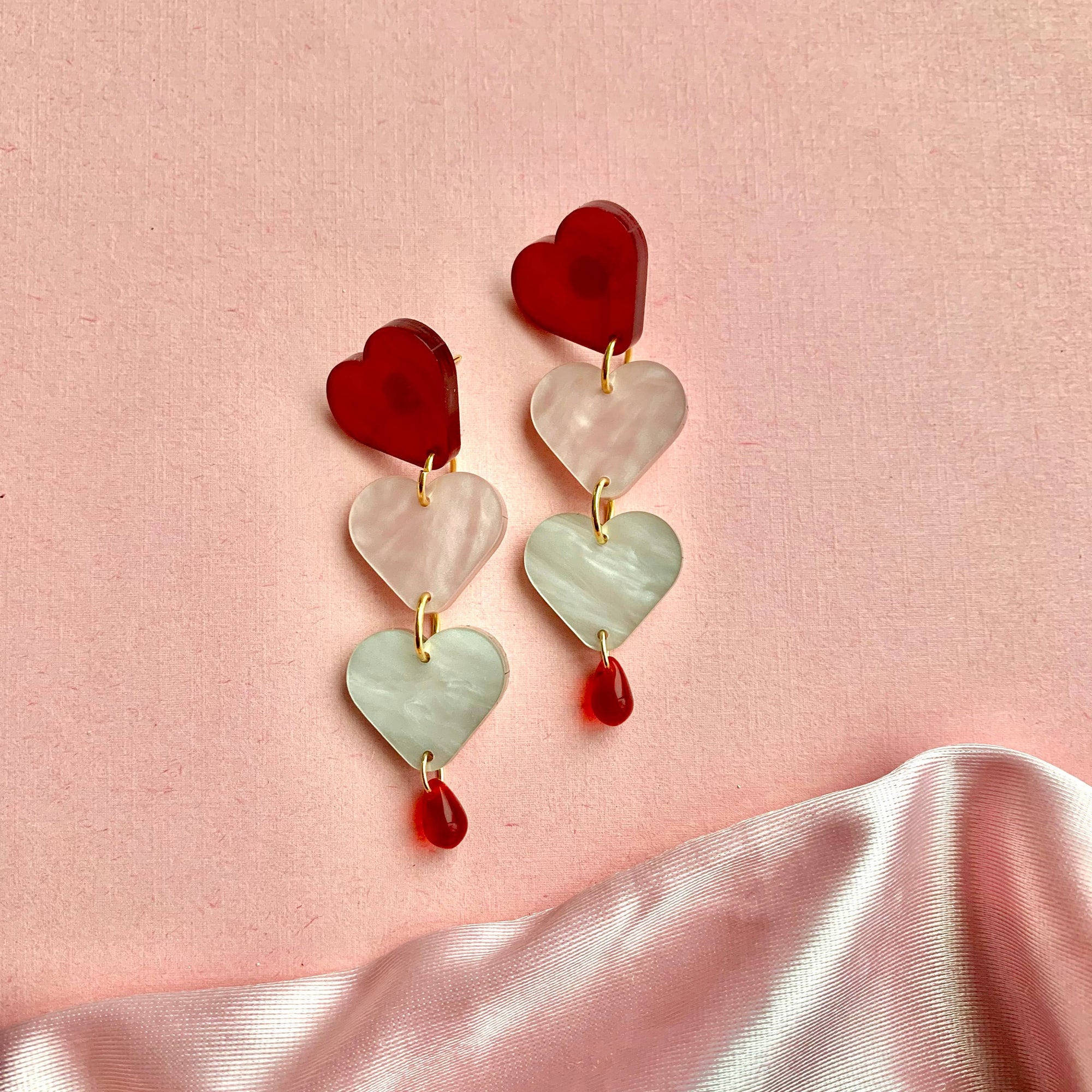 Heart-shaped earrings on a pink fabric background