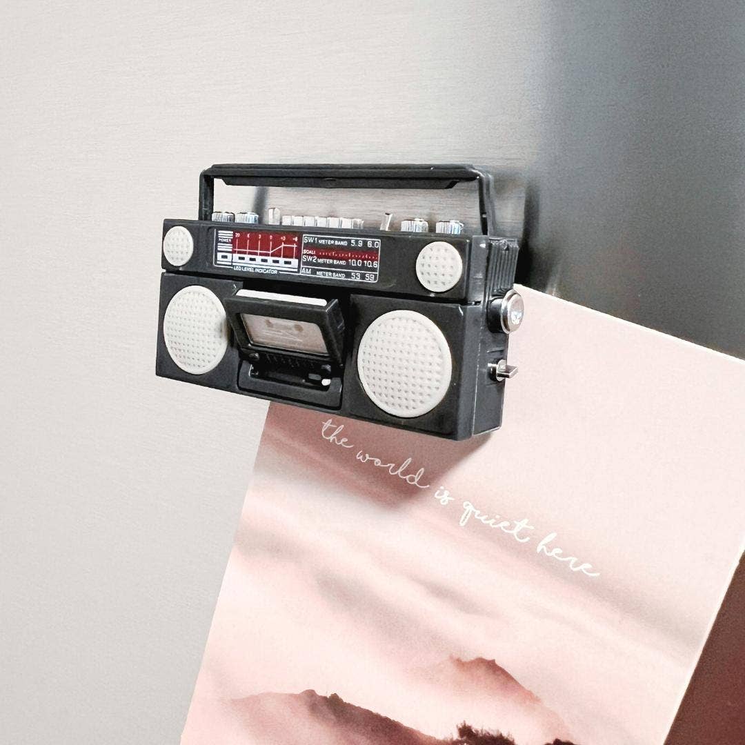 Vintage-style black radio with white knobs on a light gray background