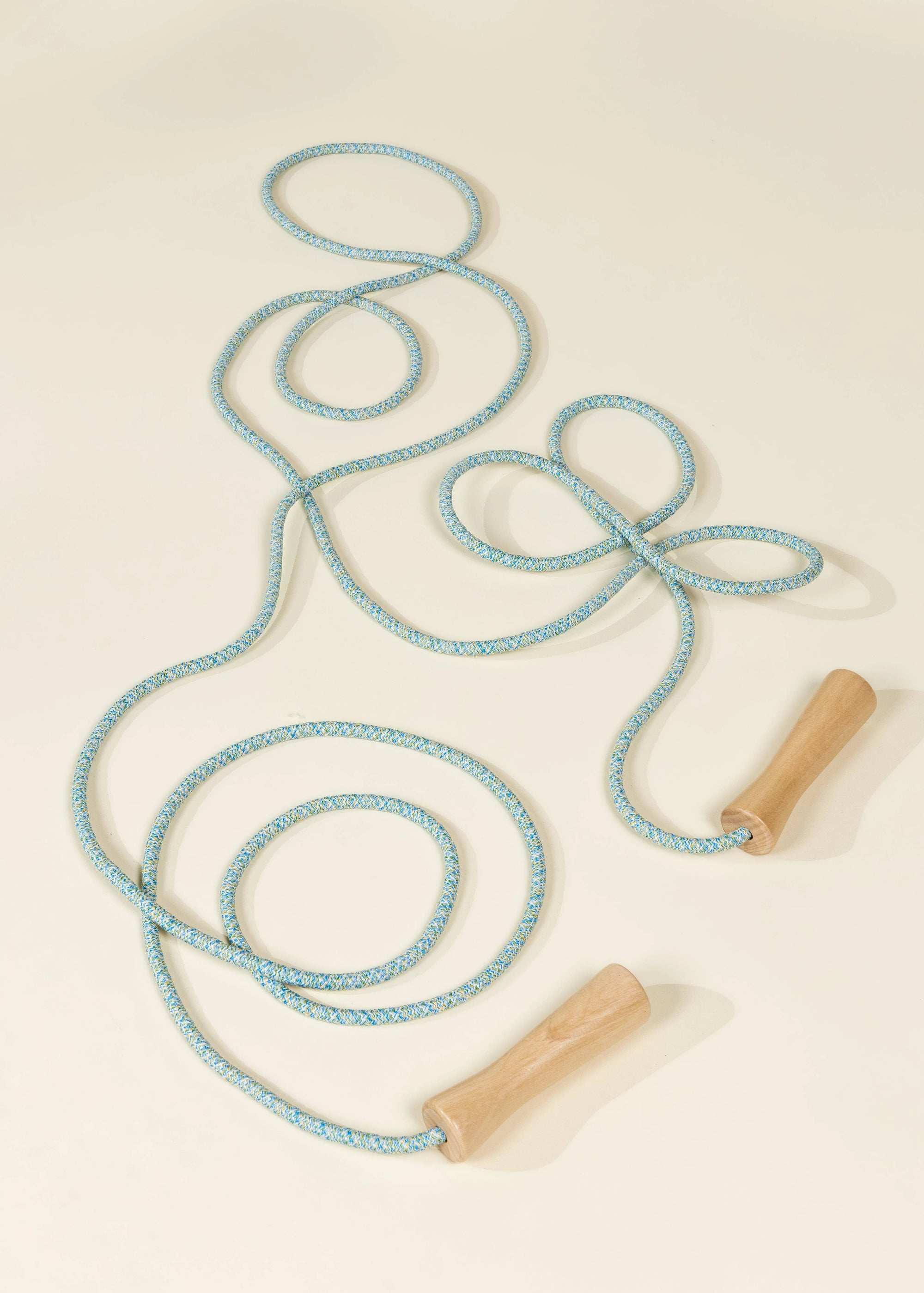 Light blue跳绳 with wooden handles on a beige background
