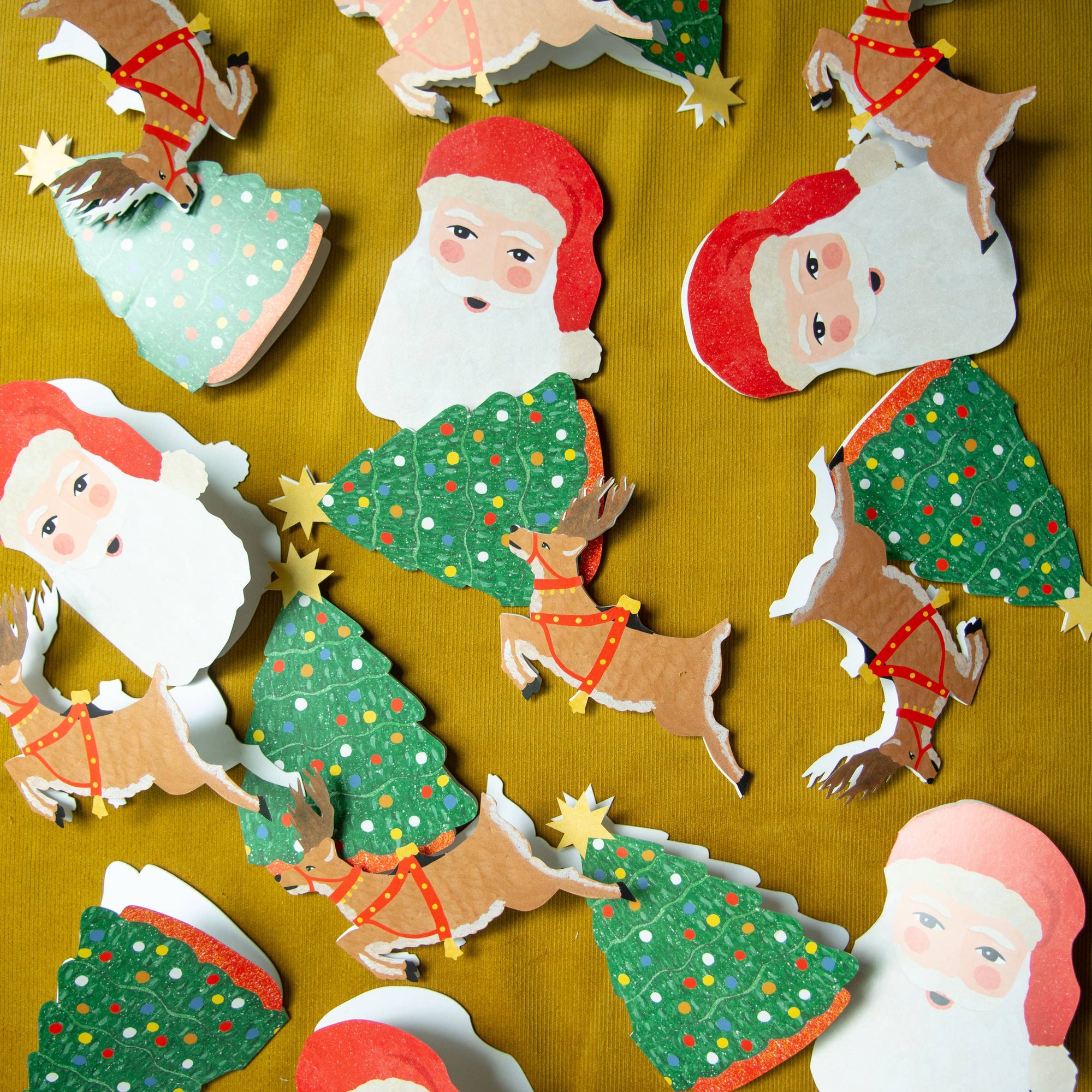 Collection of Christmas-themed cutouts including Santa Claus, reindeer, and trees on a yellow background.