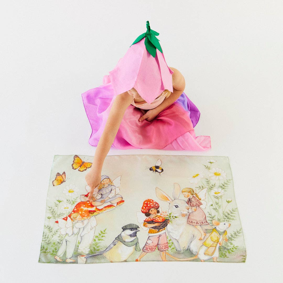 Person in a pink dress with a flower hat on top of a colorful rug with illustrations.