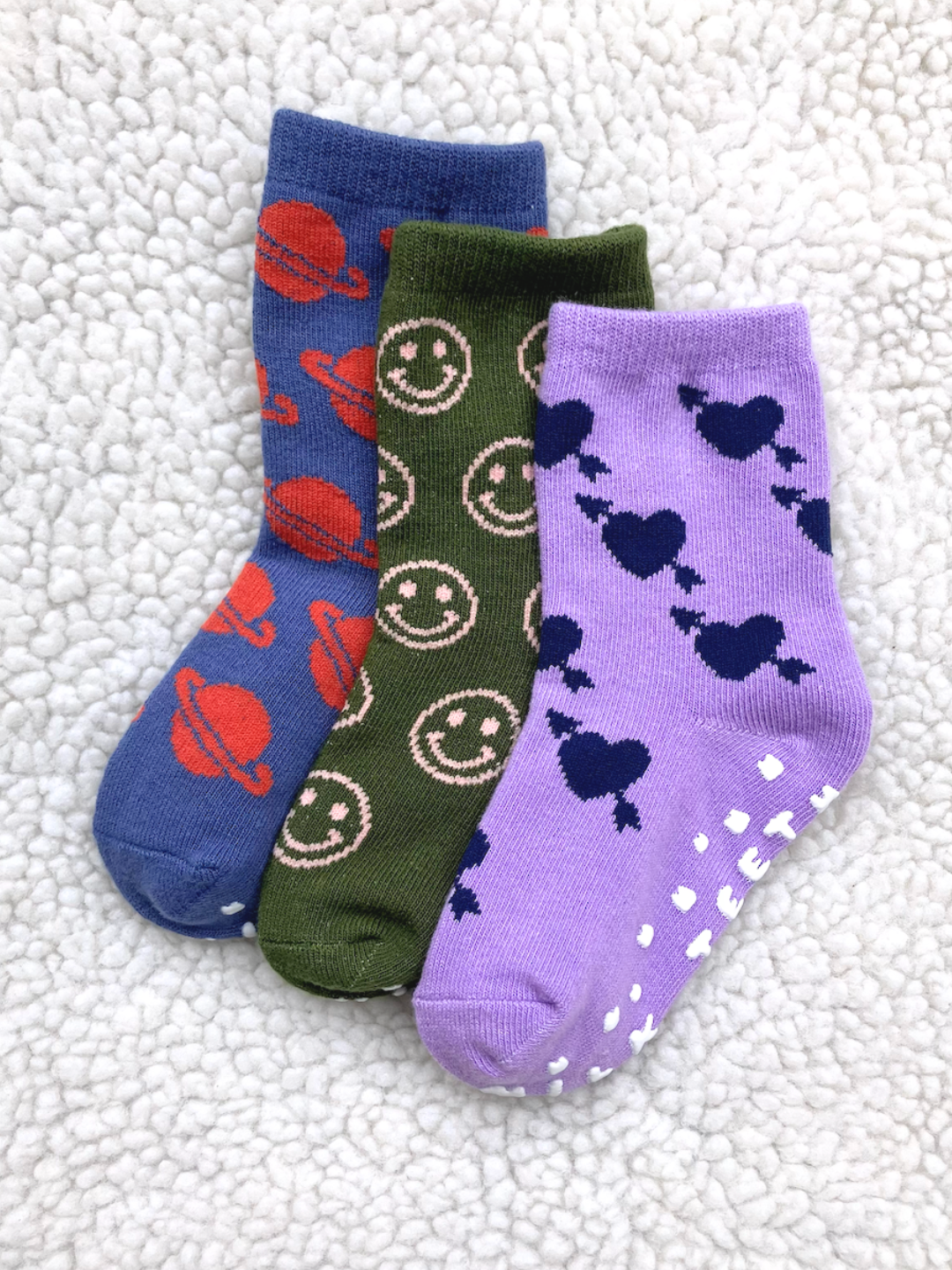 Three pairs of colorful socks with patterns on a textured white background