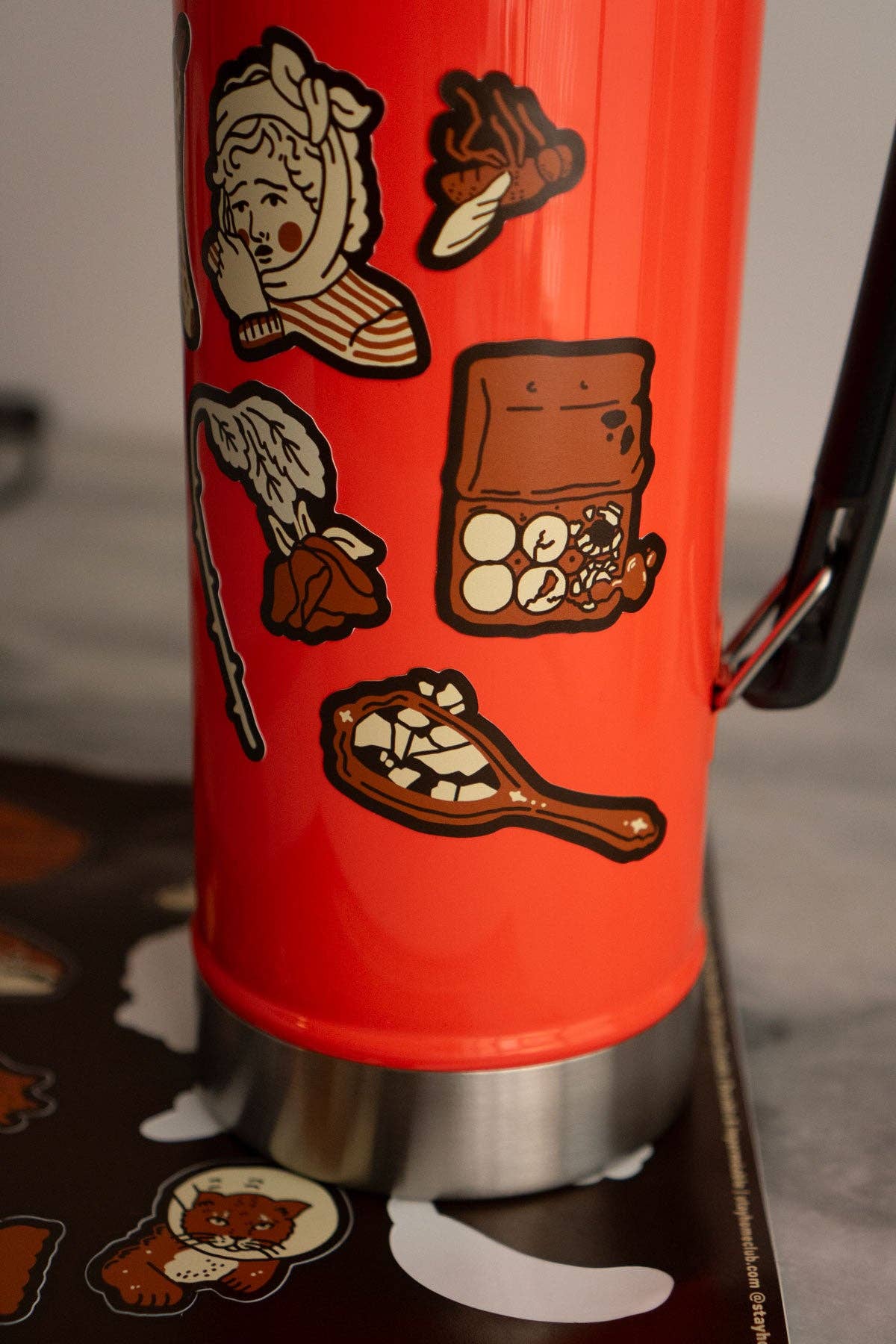 Red thermos with cartoon character and food illustrations on a dark surface