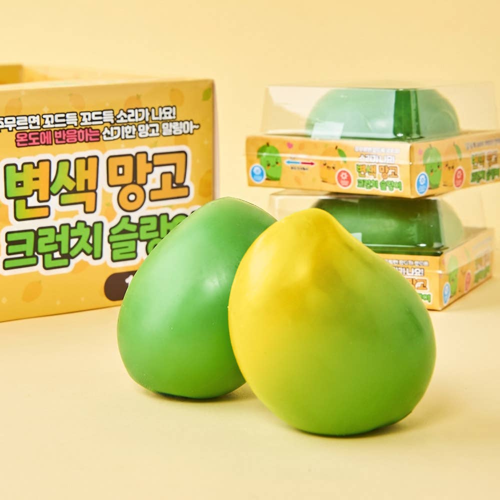 Two squeeze toys shaped like peaches, one green and one yellow-green, shown in front of their colorful packaging boxes on a light beige background.