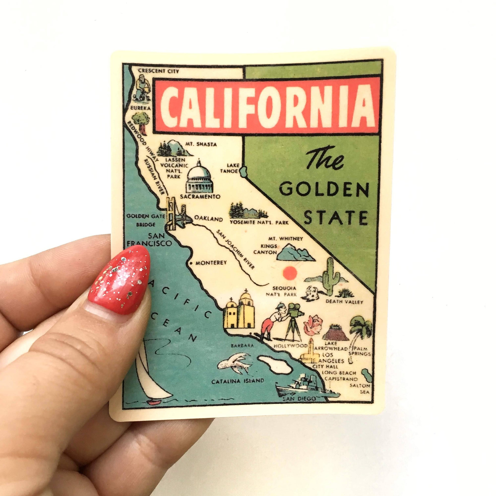 Map of California held by a hand with red nail polish on a white background