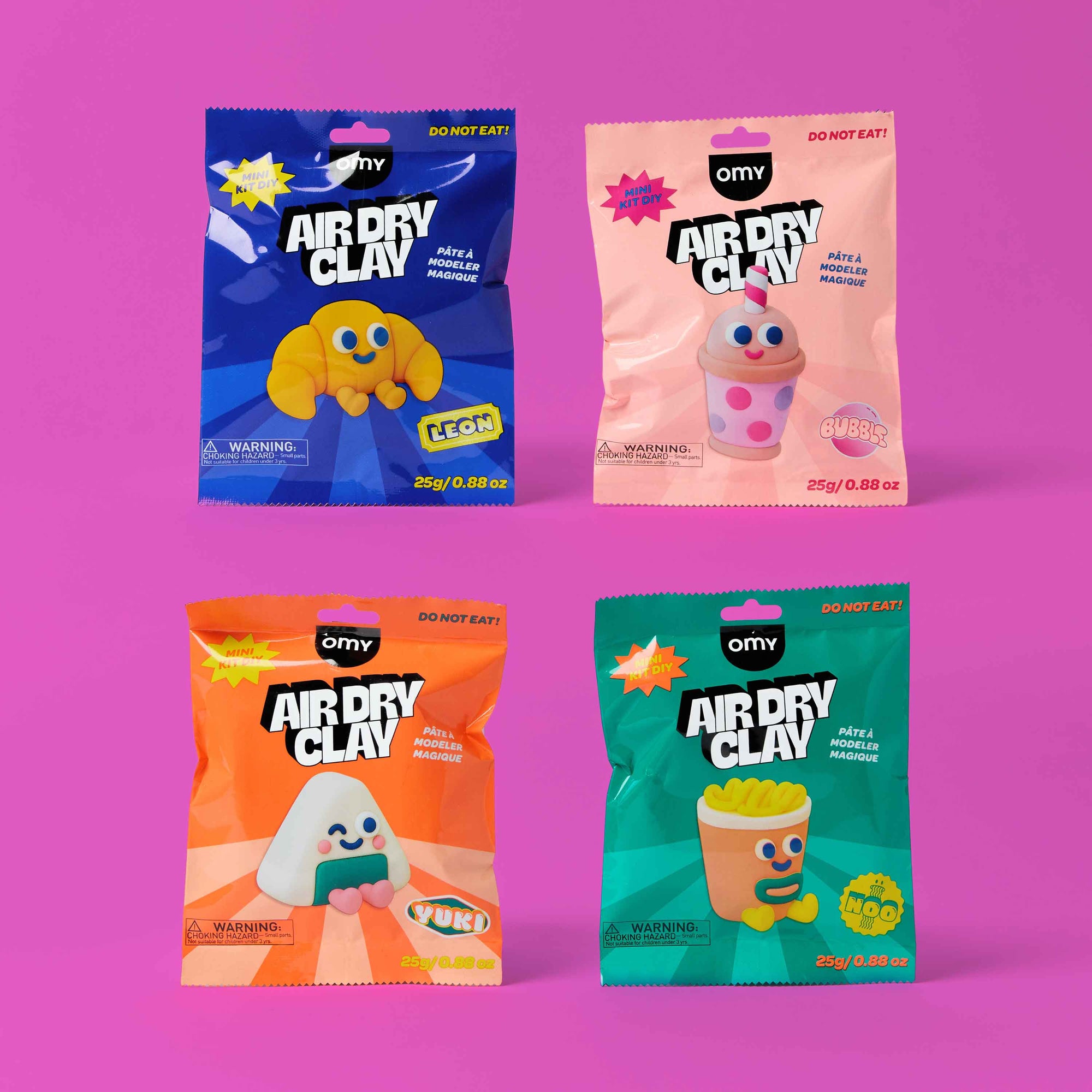 Four packages of OMY Air Dry Clay on a pink background