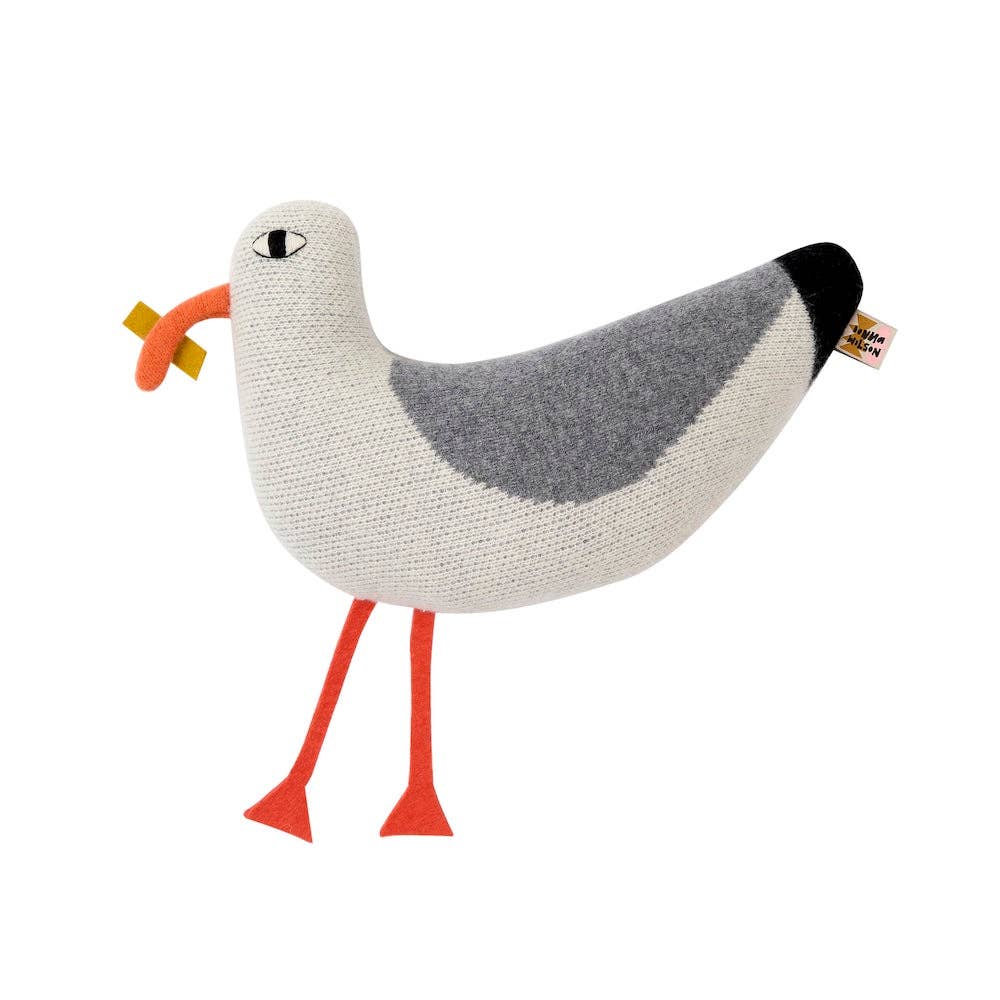 Knitted seagull toy with a white body, gray wings, and orange legs on a white background