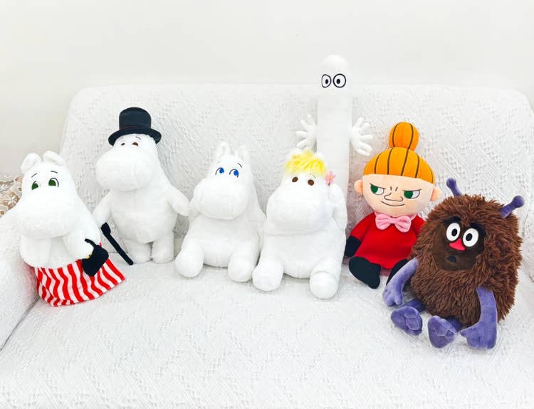 Plush toys resembling characters from the Moomin series on a white background