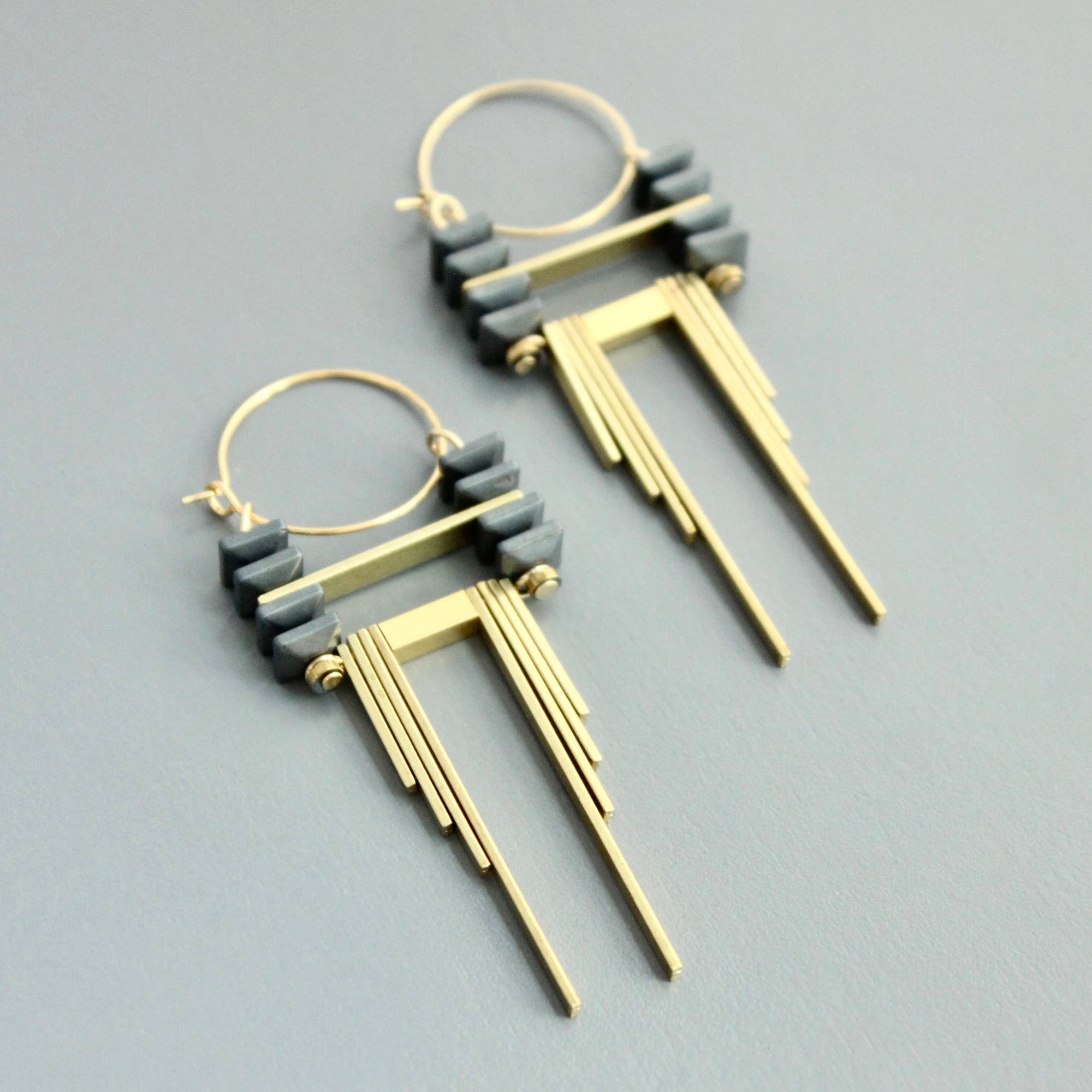 Gold and gray earrings on a light gray background