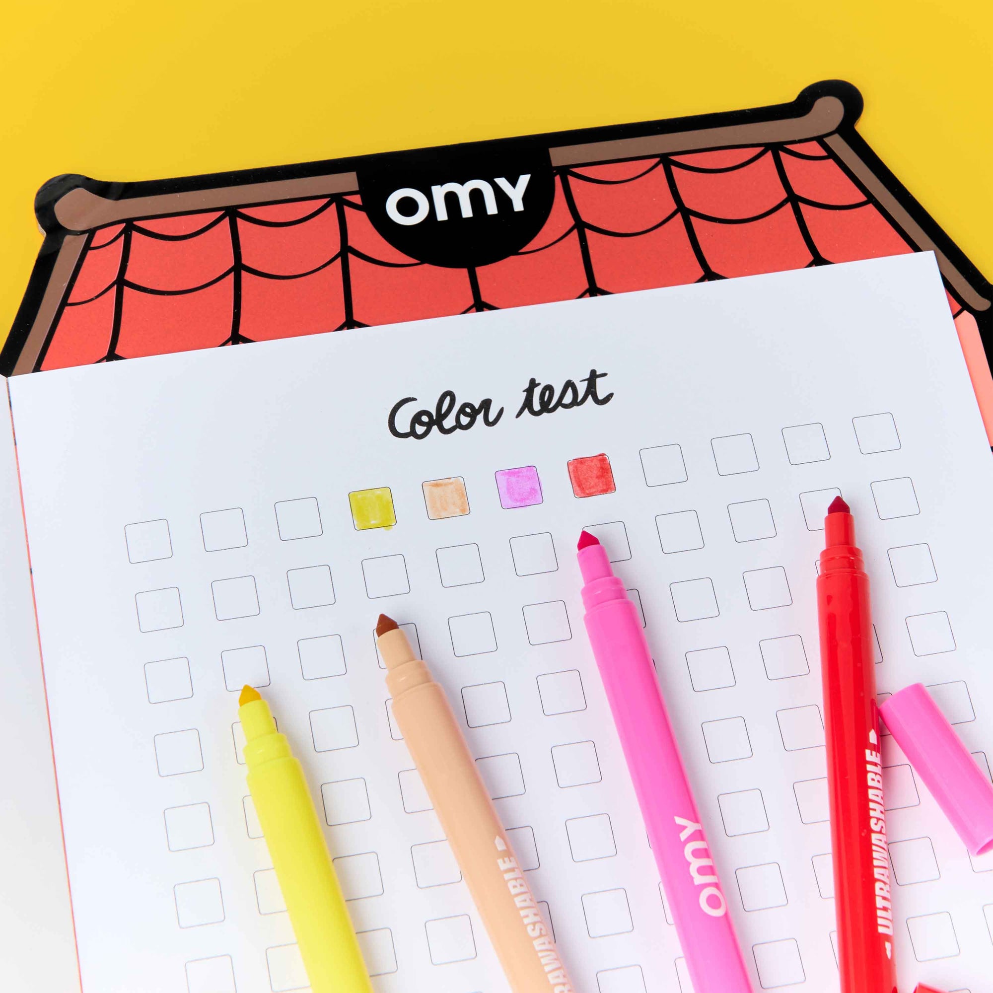 Color test sheet with markers on a yellow background, featuring the brand 'omy'.