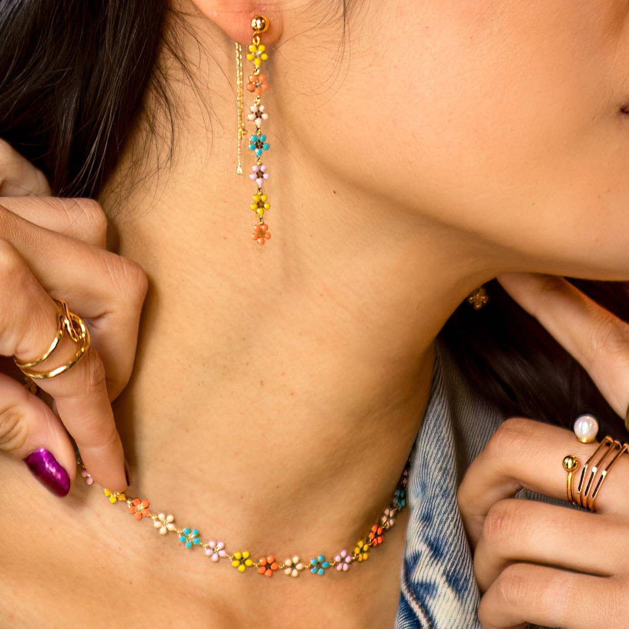 Close-up of a person wearing colorful beaded earrings and a necklace.