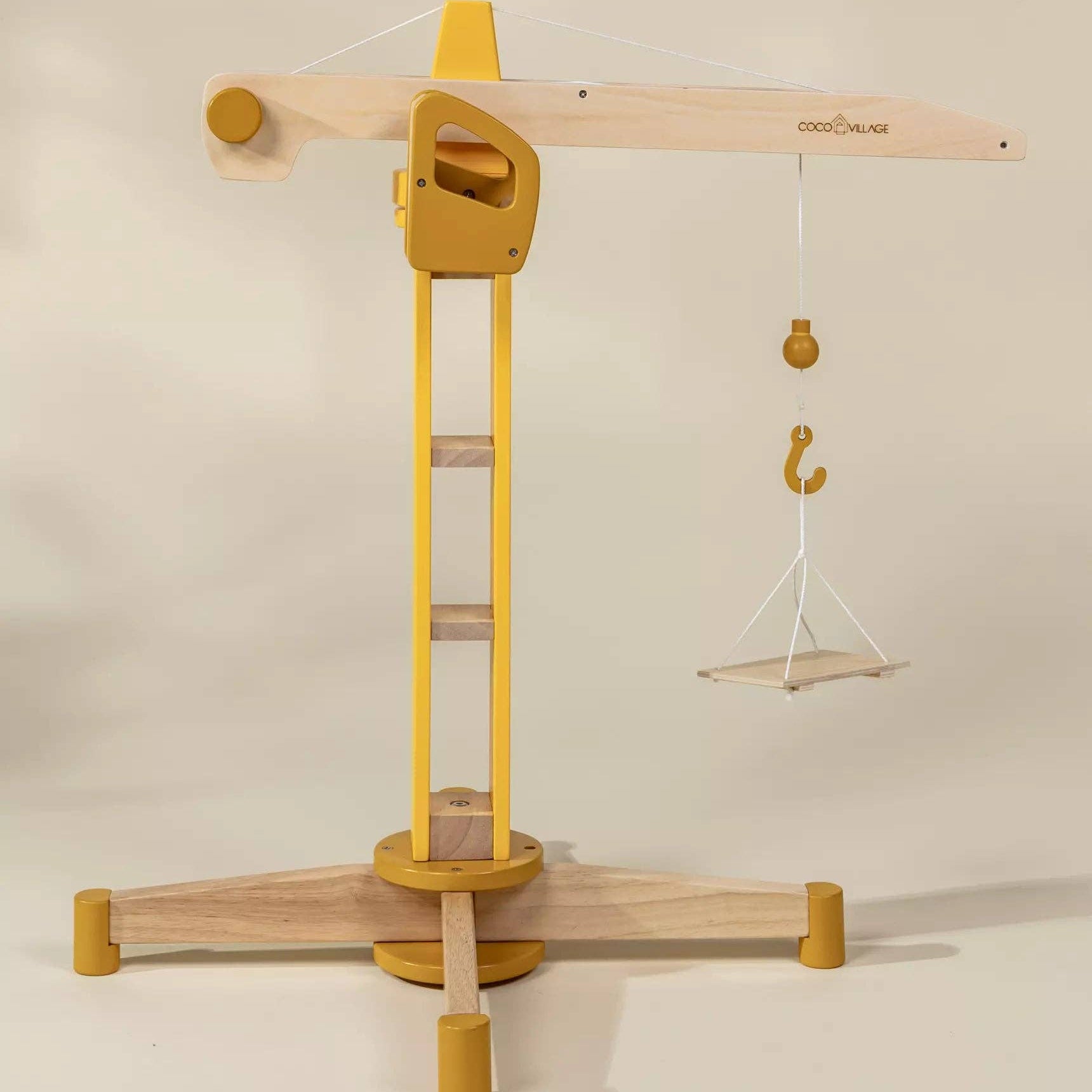 Wooden toy crane with yellow accents on a beige background