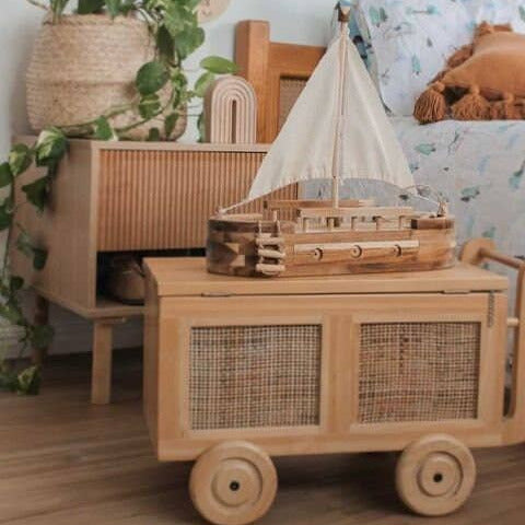 Wooden toy boat on a cart in a child's room with decorative elements.