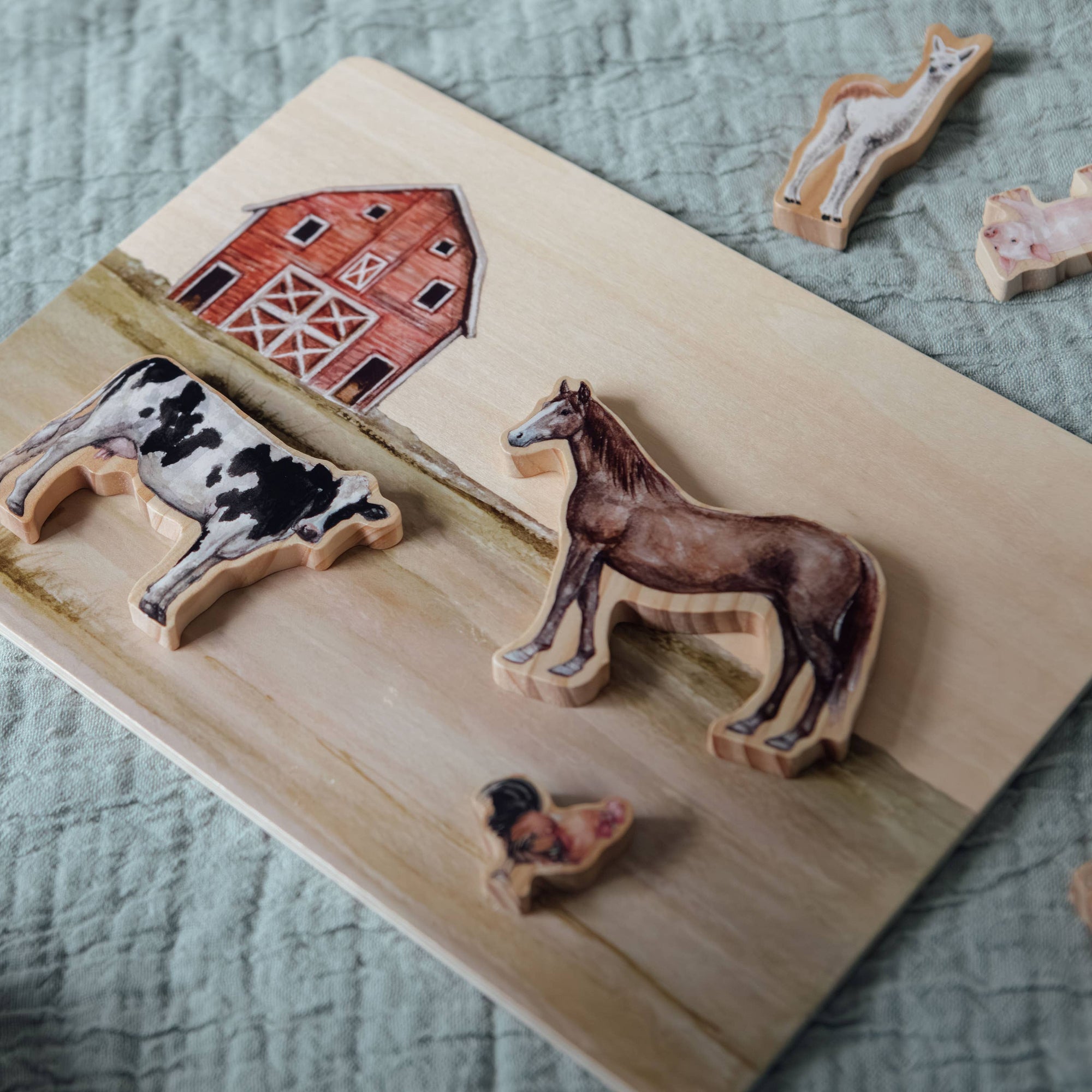 Wooden farm scene with animal figures on a textured surface