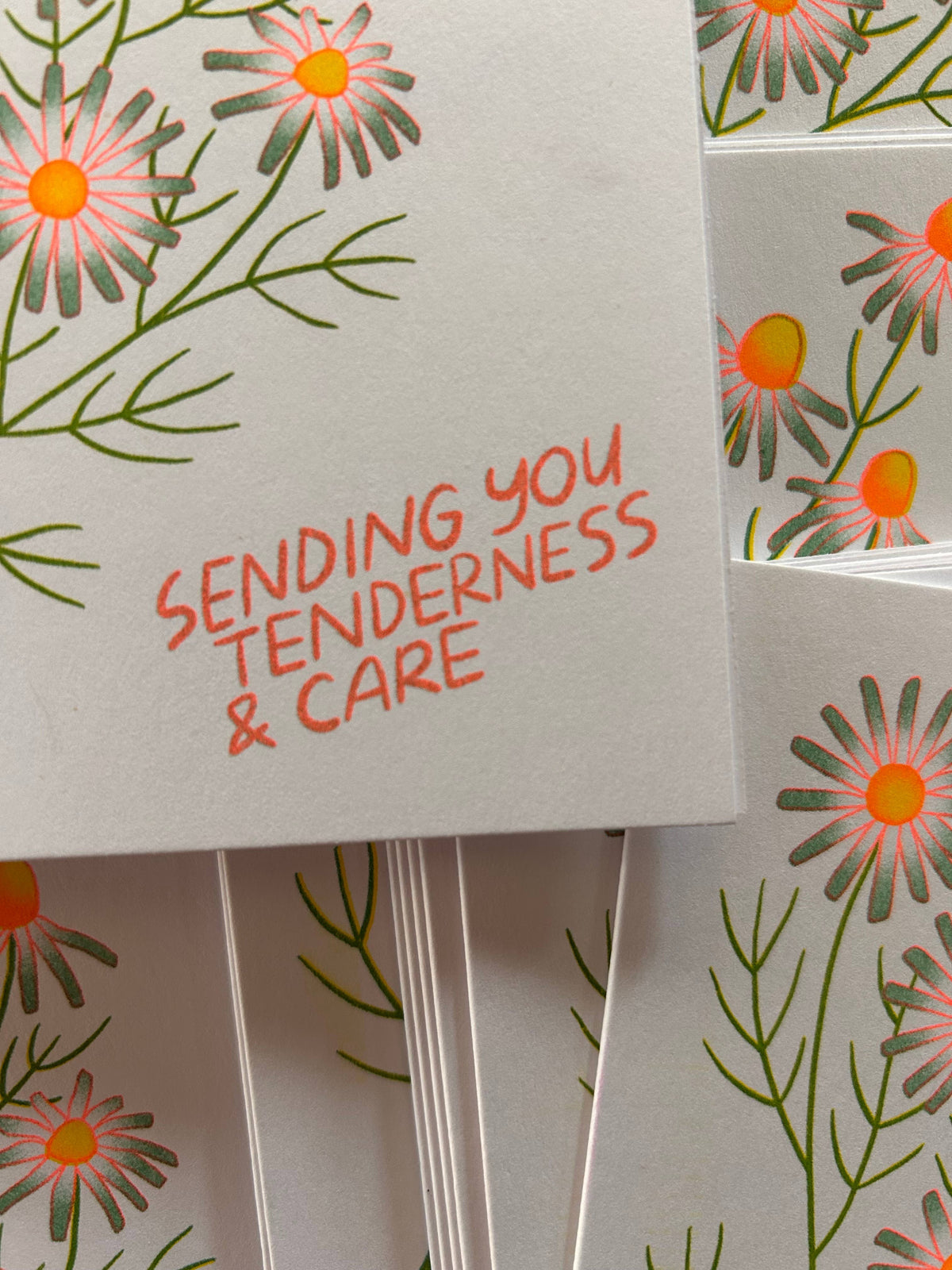 Card with floral design and text 'Sending you tenderness & care' on a matching background.