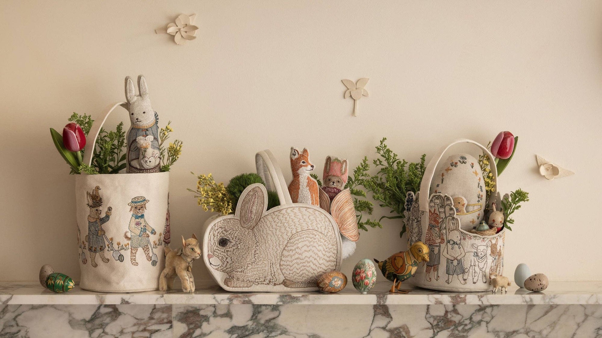Decorative shelf with ceramic baskets, rabbits, and flowers on a marble surface.