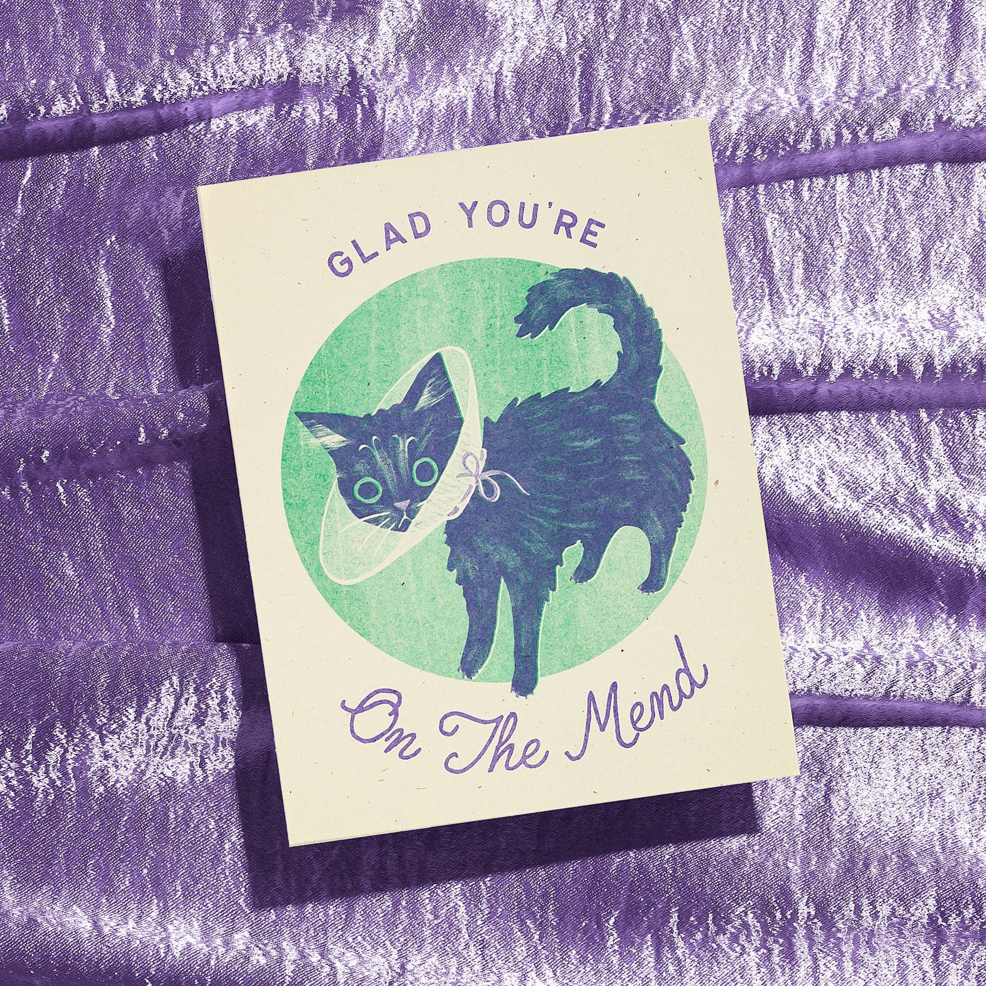 Card with a cat illustration and text 'Glad You're On The Mend' on a textured purple background