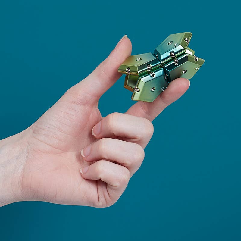 Hand holding a metallic object against a teal background