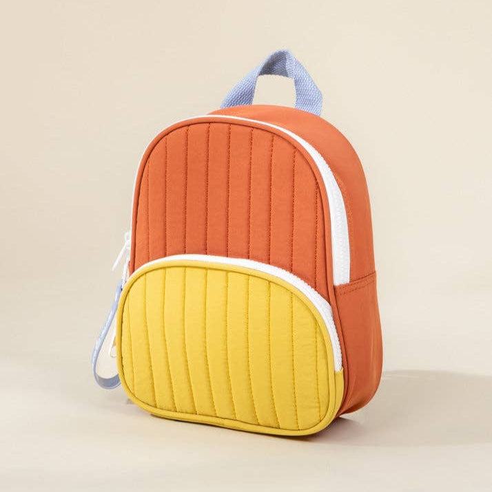Colorful backpack with orange and yellow design on a beige background