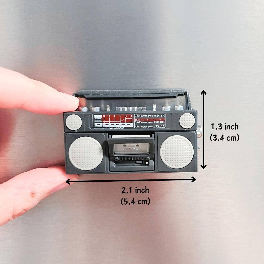 Miniature retro-style radio and cassette player held by a hand with measurements indicated.