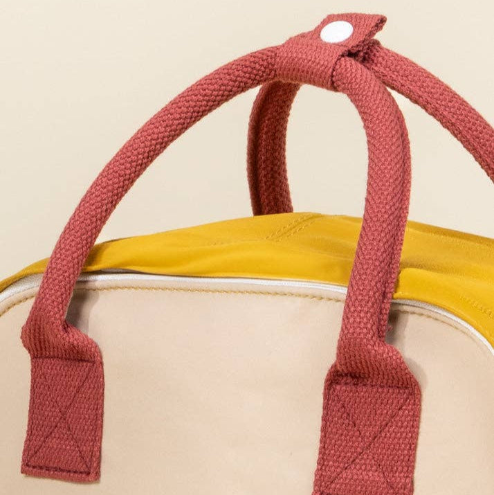 Close-up of a bag with brown handles on a beige background