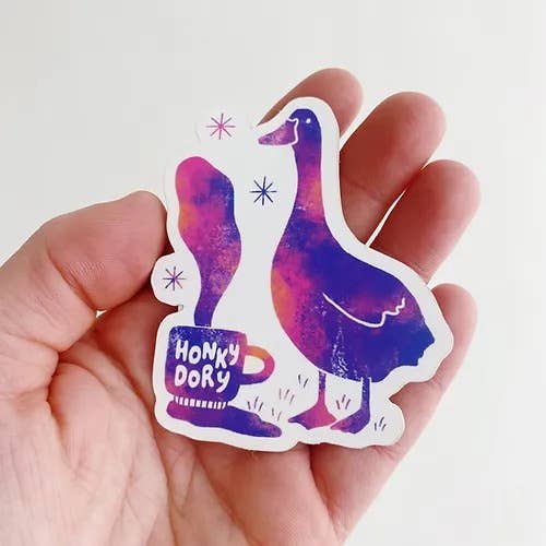 Hand holding a colorful sticker with a goose design and 'Honky Dory' text.