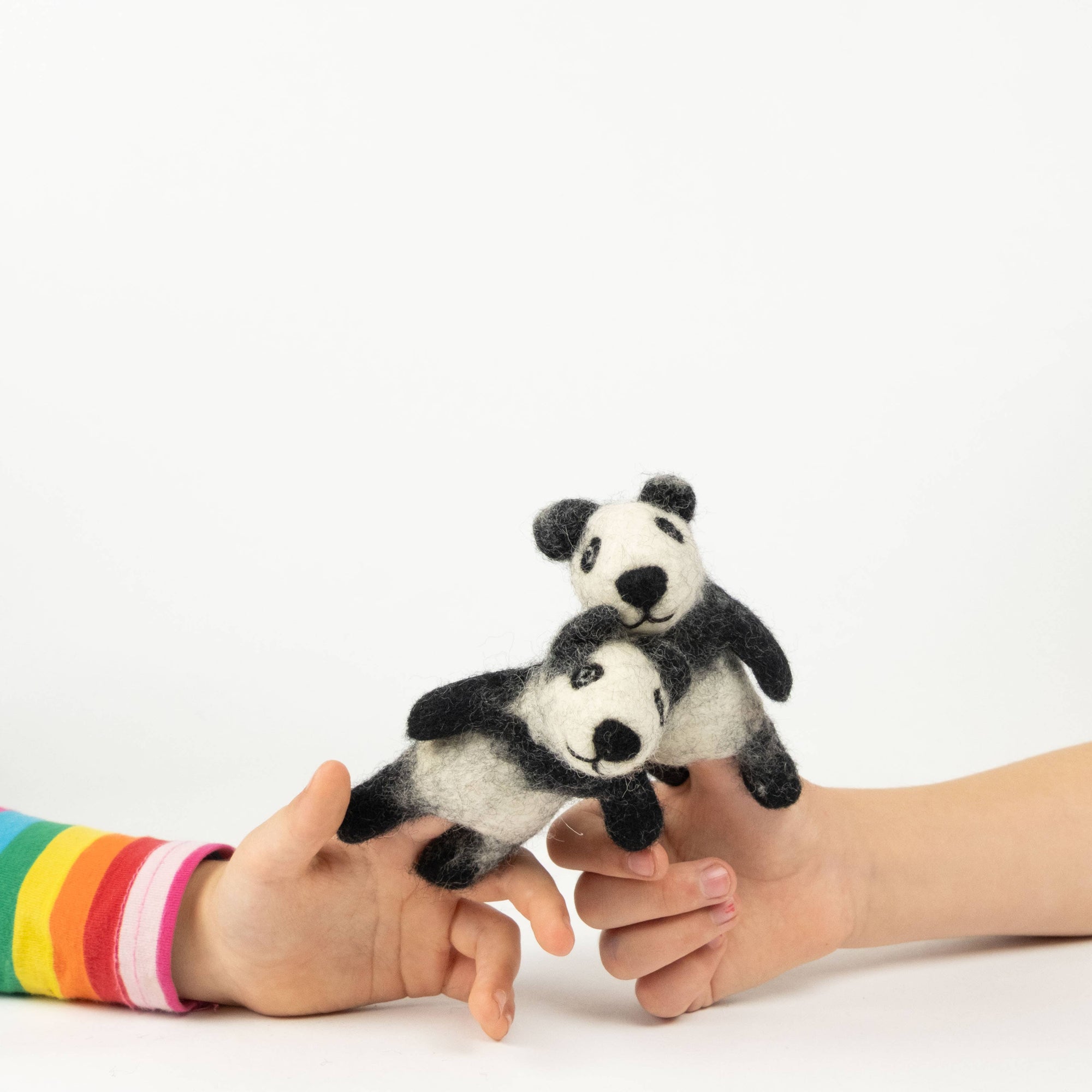 Two panda finger puppets on a child's hands against a white background
