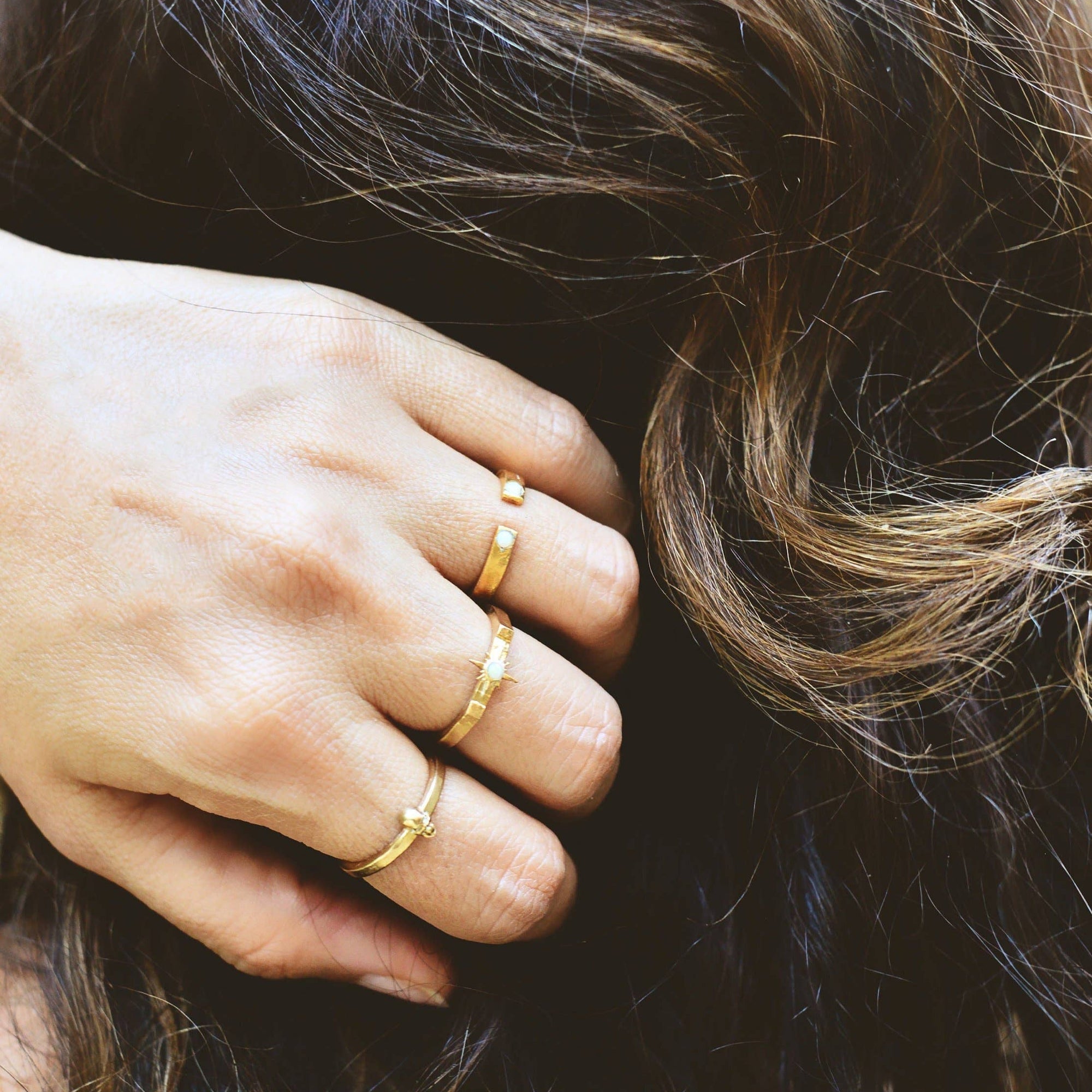 Close-up of a hand with gold rings on a blurred background