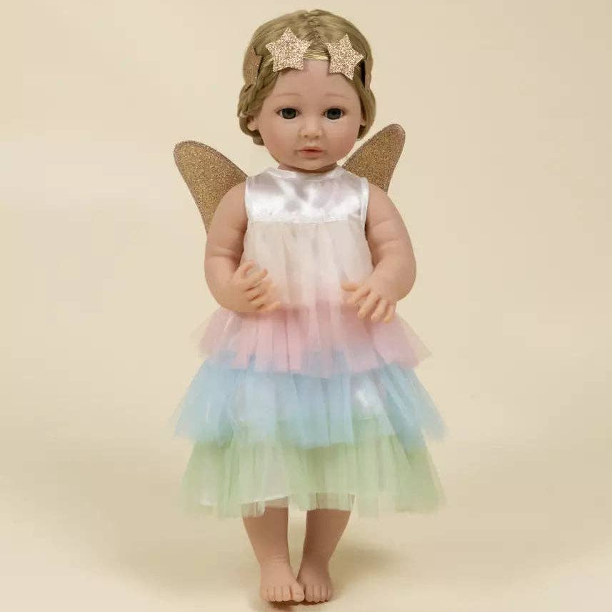 Doll in a pastel fairy costume with wings and a headband on a beige background