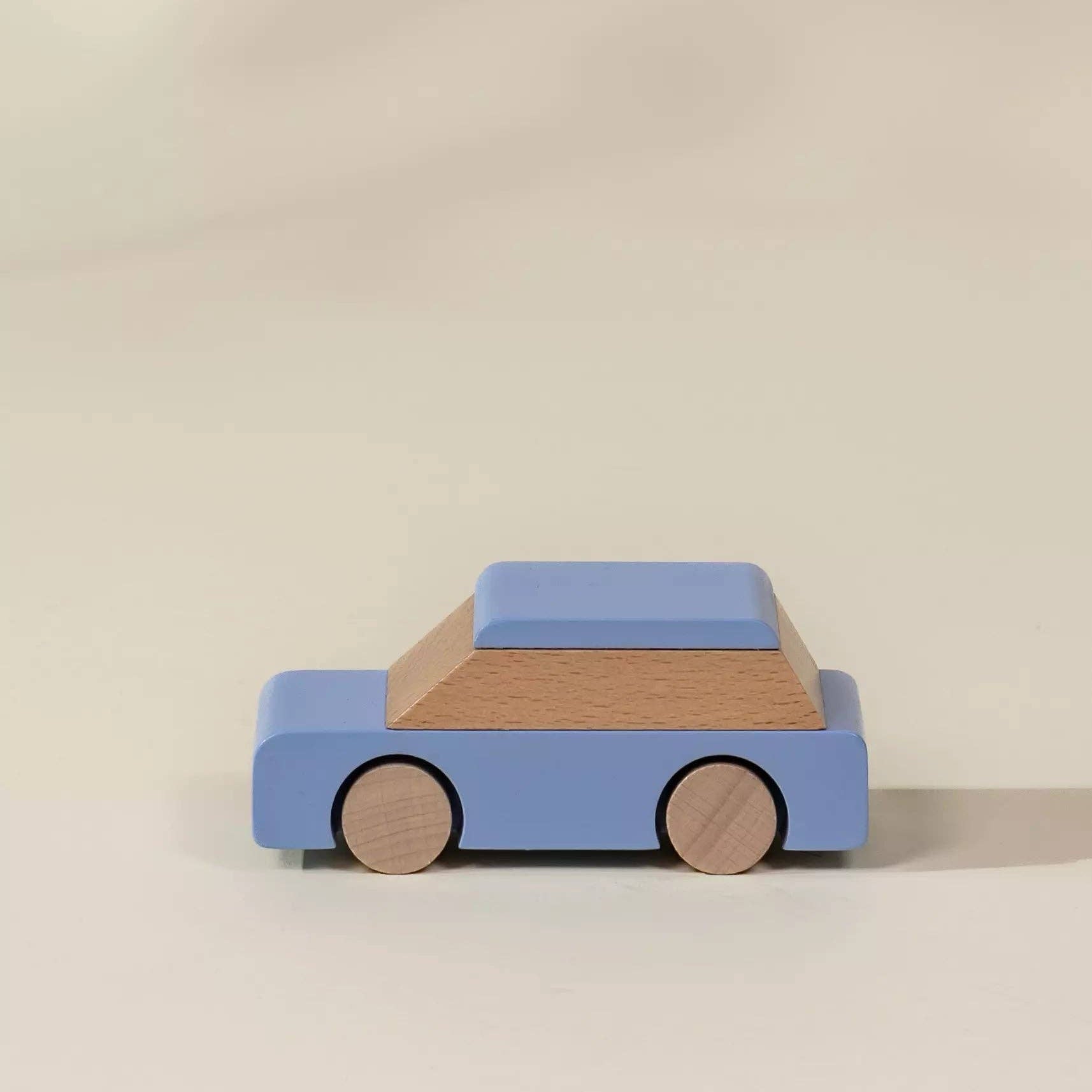 Wooden toy car with a blue body and brown roof on a beige background