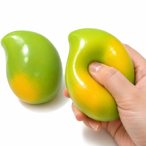 Two green-and-yellow mango-shaped stress toys on a white background, with one being squeezed by a hand.