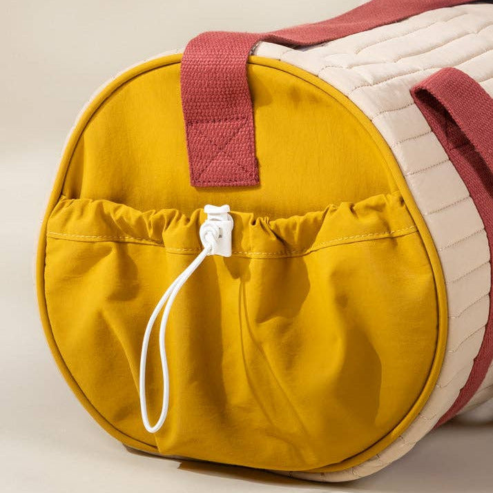 Multicolored cylindrical bag with a yellow front pocket on a beige background