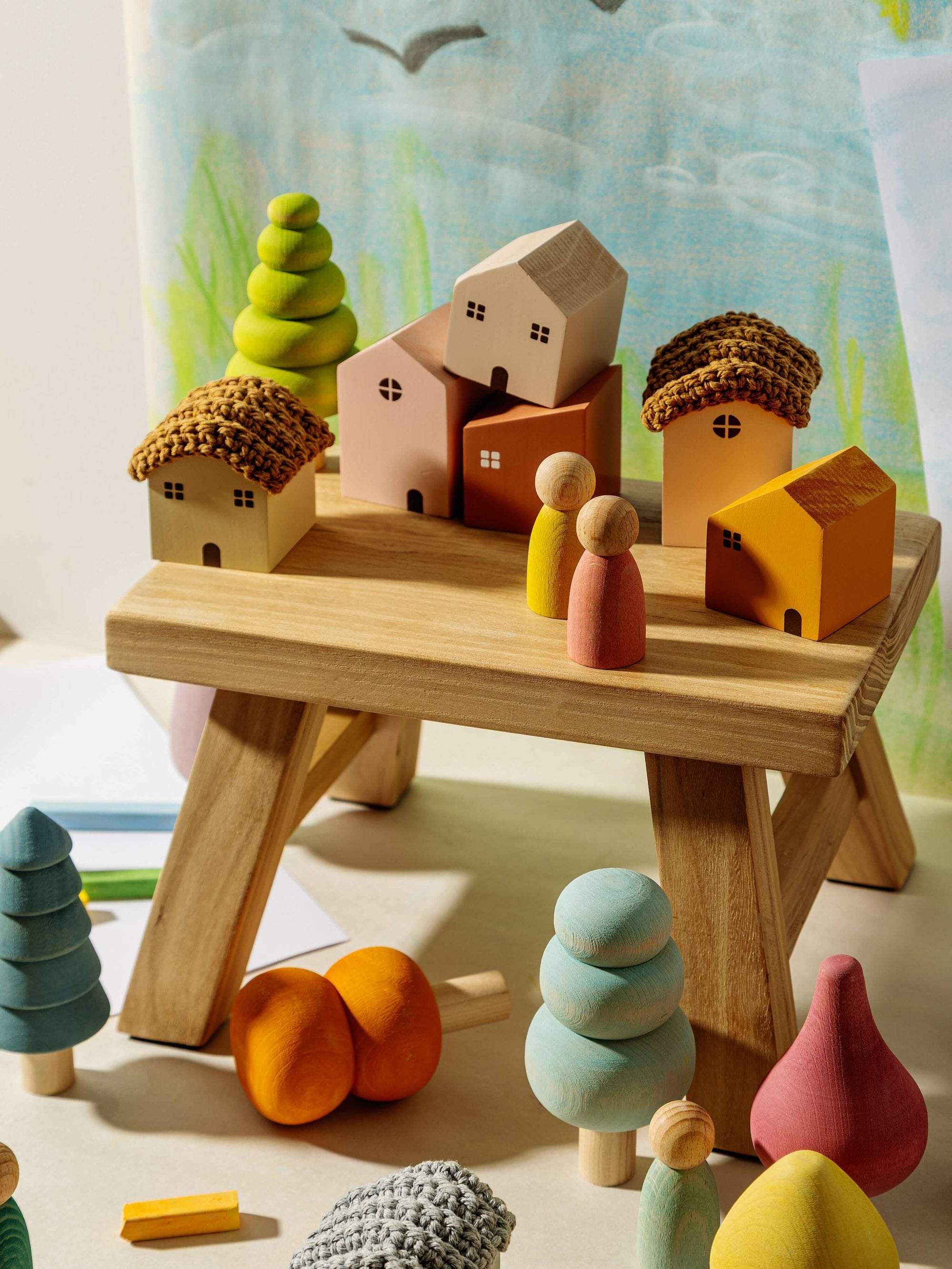 Wooden toy set with houses, trees, and people on a wooden platform.