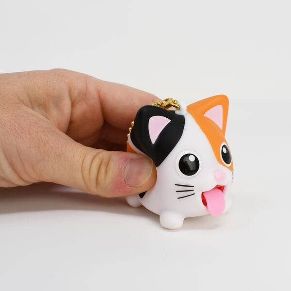 Hand holding a small cat-shaped keychain with orange and black ears on a white background