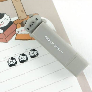 Cute cat-shaped stamp on a notebook with cartoon illustrations of cats.