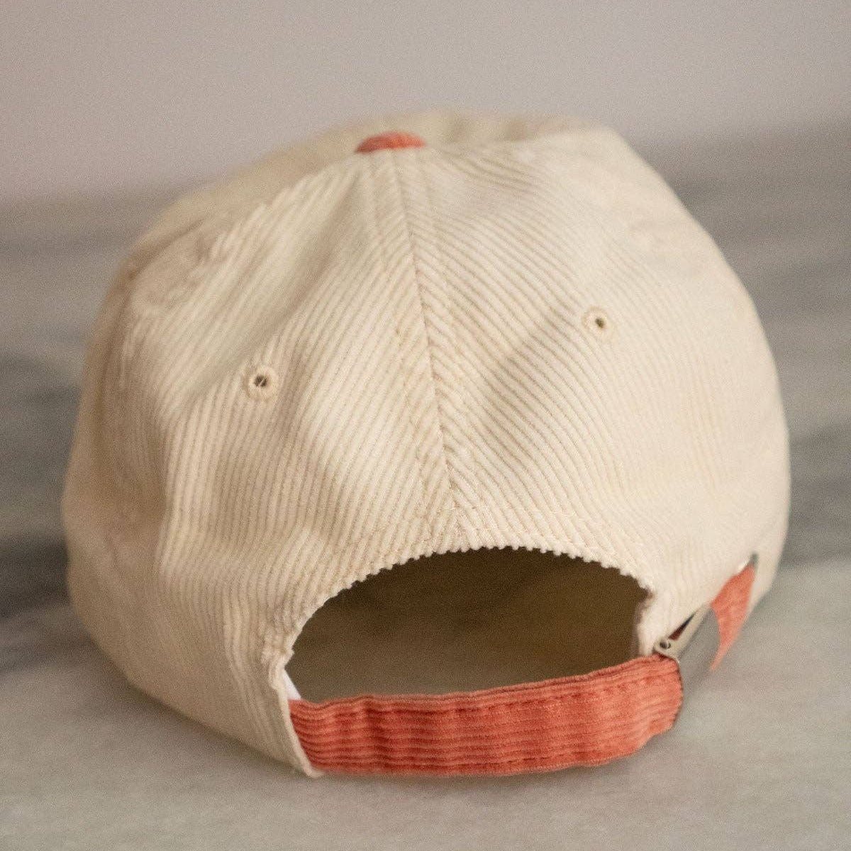 Beige cap with red interior on a gray surface